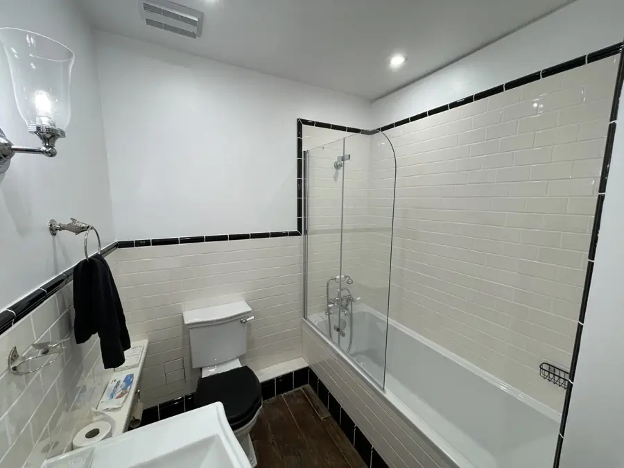 Bath with folding glass screen and black tile border